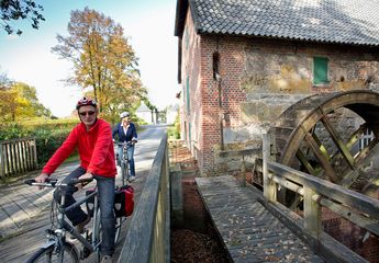 Zwei Radfahrer passieren die Wassermühle Gartrop in Hünxe