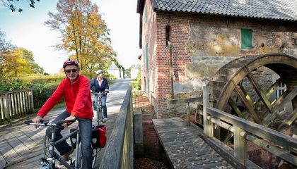 Zwei Radfahrer passieren die Wassermühle Gartrop in Hünxe