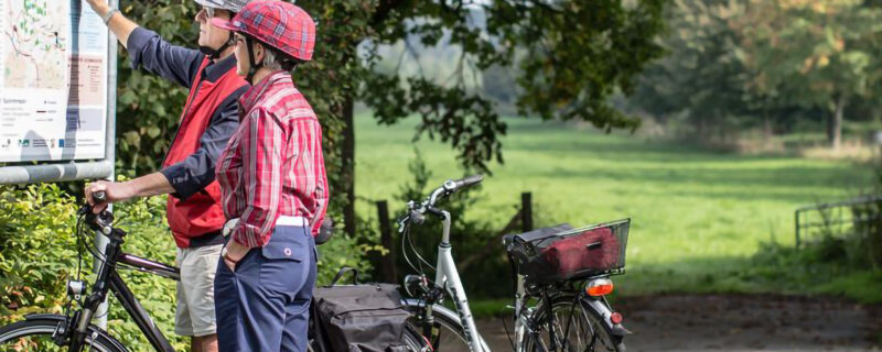 Ein Radfahrer Paar informiert sich über die Wegeführung eines Radweges