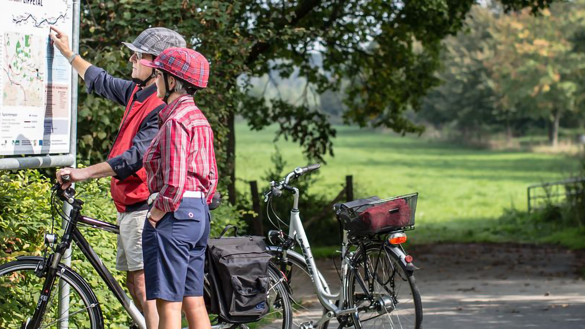 Ein Radfahrer Paar informiert sich über die Wegeführung eines Radweges